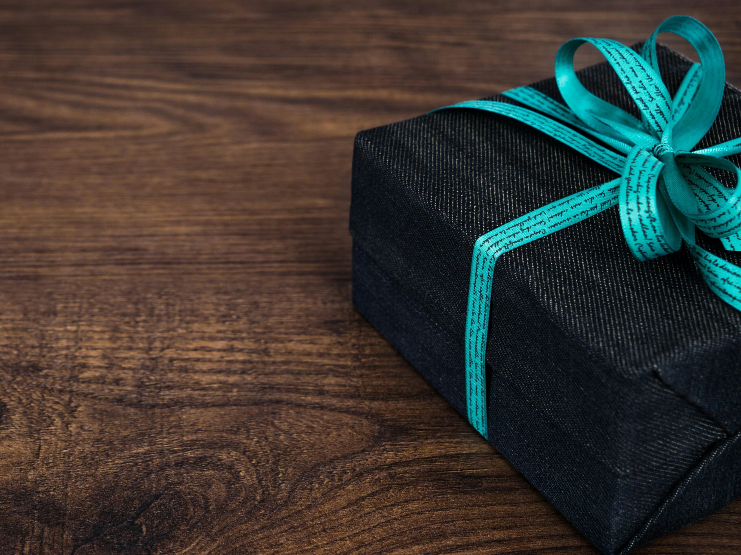 Photo of a finely wrapped gift. Photo by Pixabay: https://www.pexels.com/photo/black-gift-box-on-wooden-surface-157879/