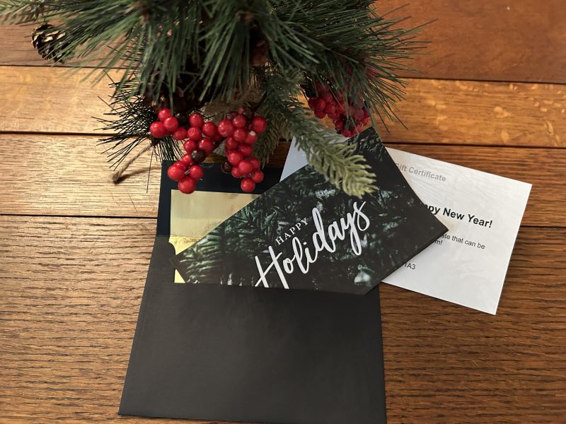 Greenery above a black envelope and Holiday card