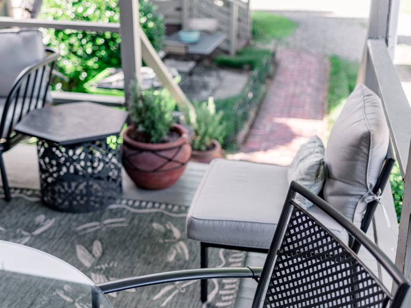 White cushion black metal chairs and terra cotta potted plant on back porch