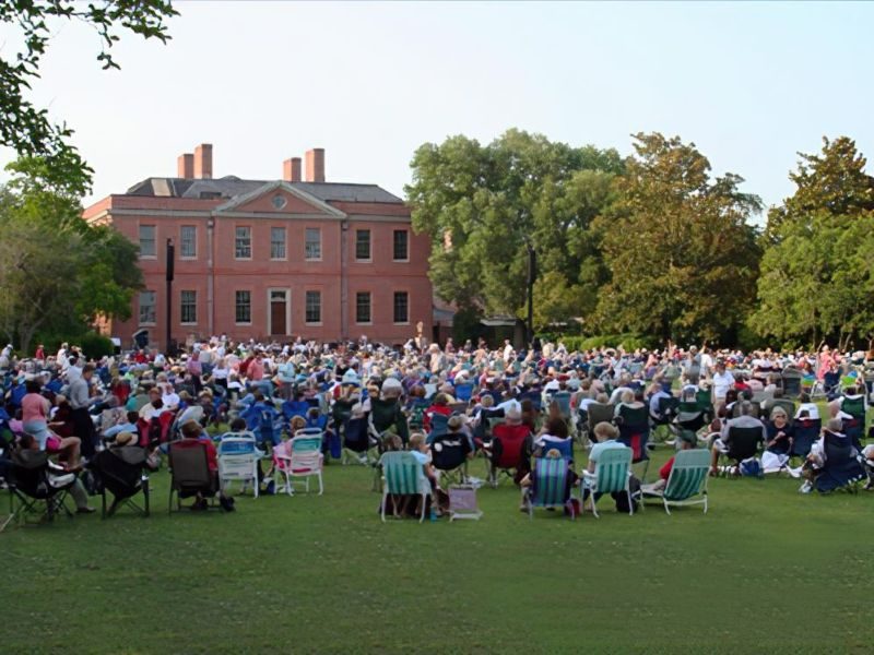 Concert-goers sitting on lawn in front of Tryon Palace